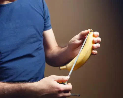 Man measuring a banana symbolizing penis size awareness